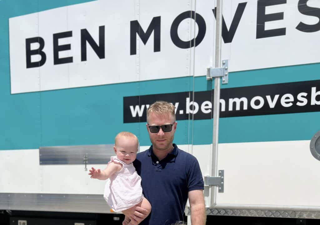 A father holding his daughter in front of a moving truck