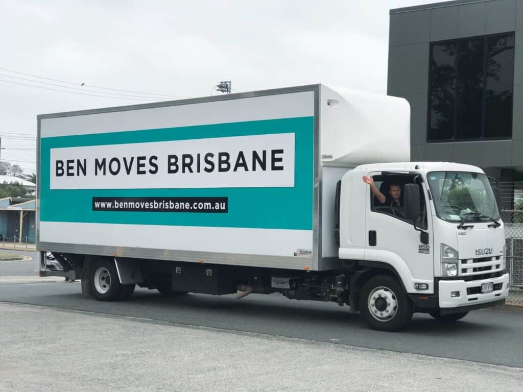 A moving truck with driver waving out of the window