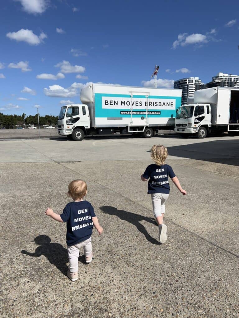 Two young children running towards a Ben Moves Brisbane truck with branded t-shirts on