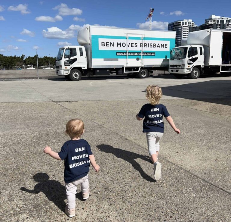 Two children running on concrete towards a moving truck