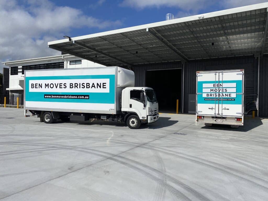 Two moving trucks labelled "Ben Moves Brisbane' parked on concrete